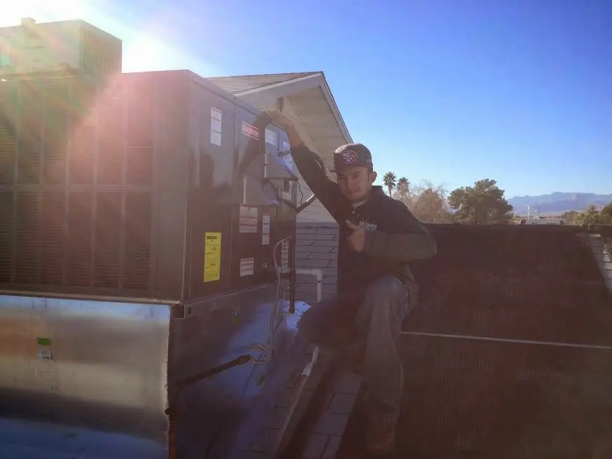 HVAC technician performing AC Tune-Up on a rooftop unit in East Moline